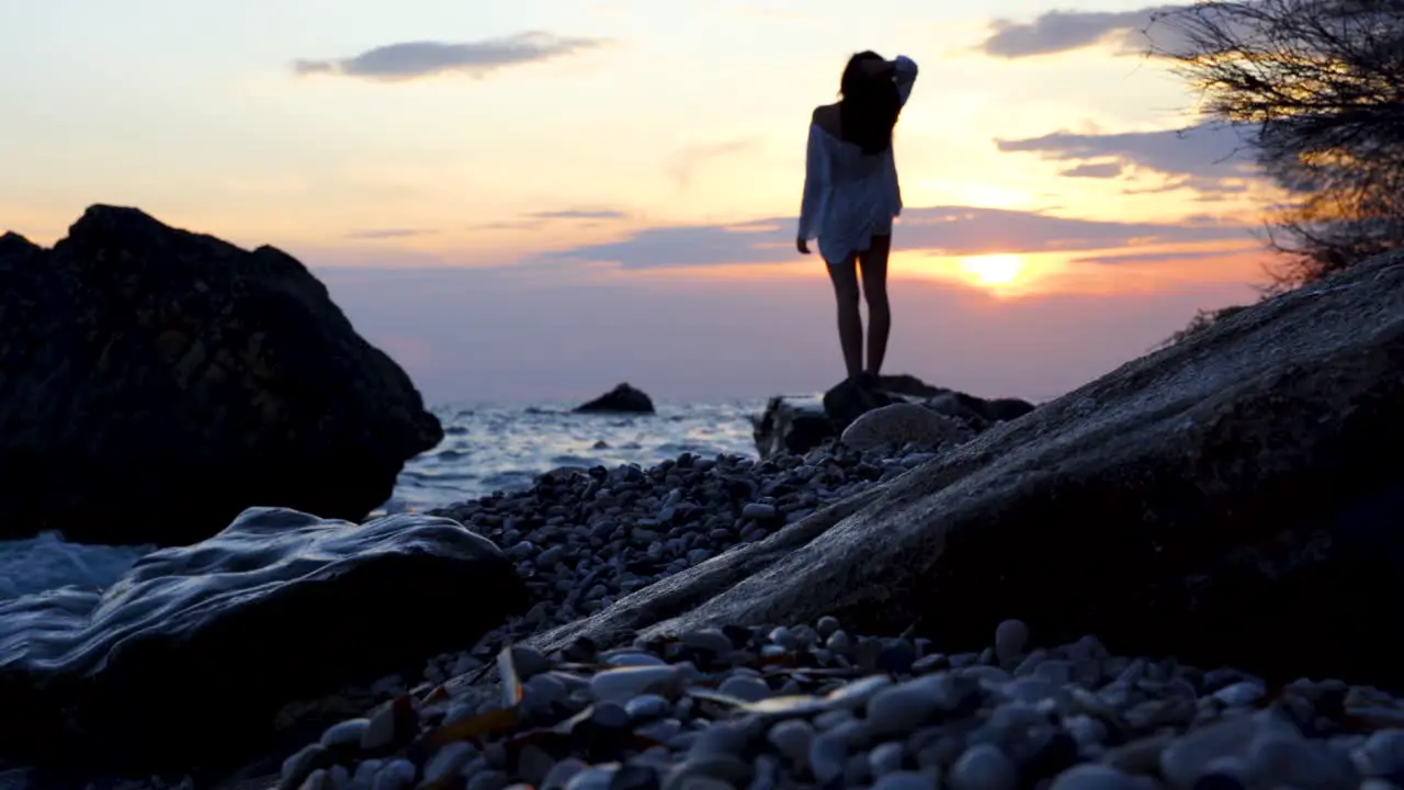 Girl watching beautiful seascape from rocky beach with cliffs splashed by sea waves