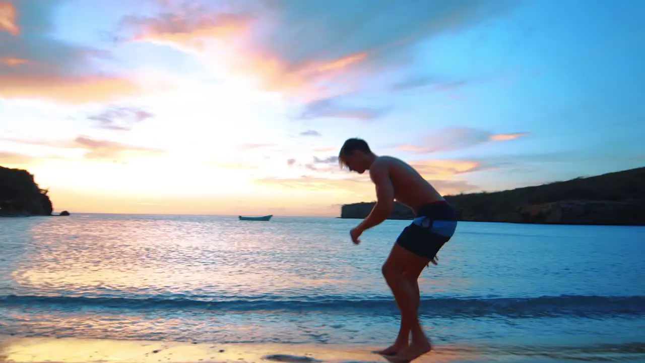 SLOWMO Man doing side flip on Caribbean beach during stunning sunset in Curacao