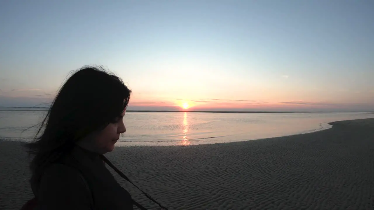 Girl with camera walking on the beach by the sunset close up slow motion