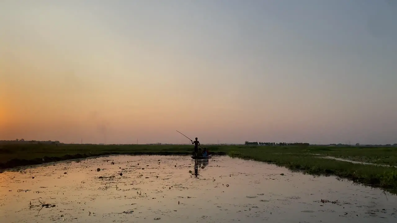 Beautiful scene of a village sunset where a man is rowing boat with passengers in a rural village lake covered with planktons