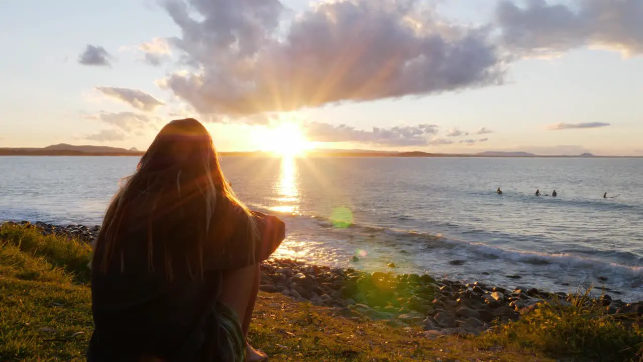 Girl Sitting And Admiring Golden Sunset Setting In The Ocean Sunset At Noosa National Park In QLD Australia