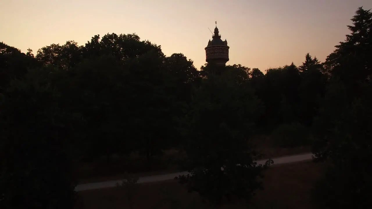 A slow and steady reveal above a small forest with water tower