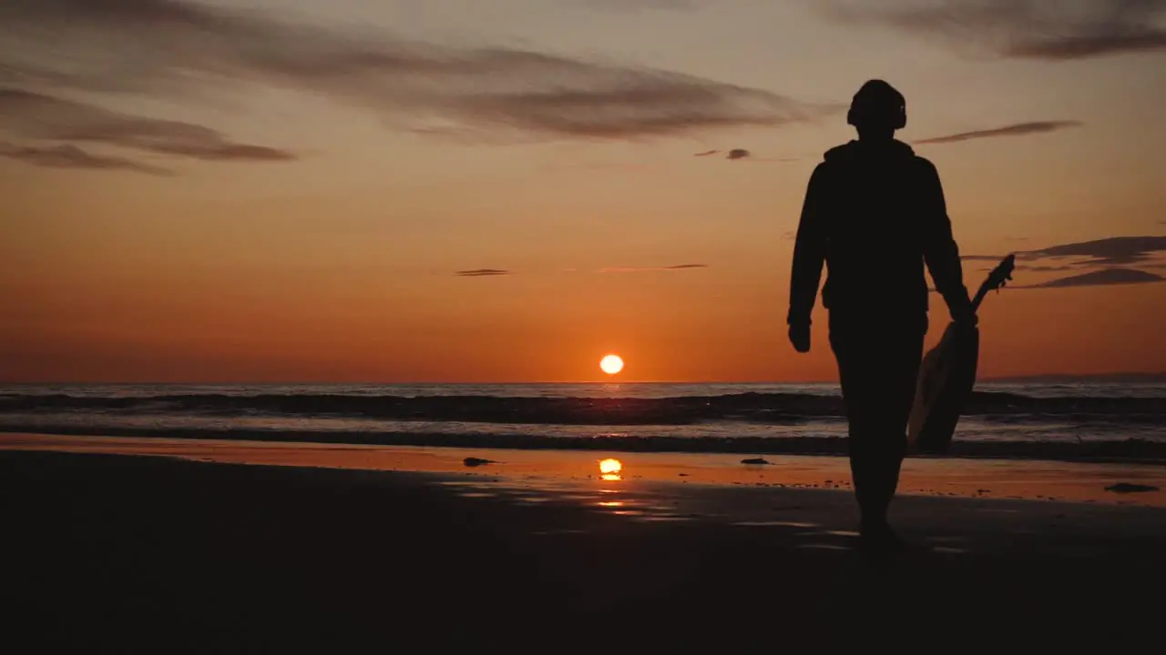 Man running with guitar in back sand beach at sunset-35