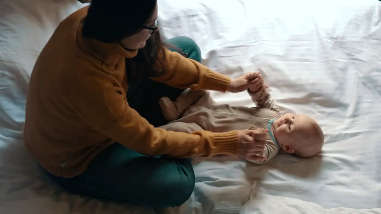 Loving mother playing with baby in bed Newborn child smiling mother