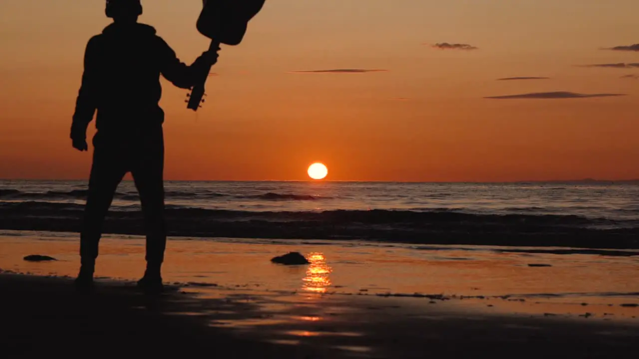 Man running with guitar in back sand beach at sunset-22