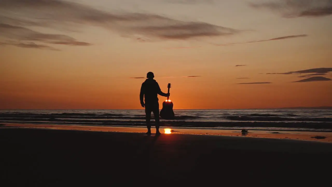 Man running with guitar in back sand beach at sunset-17