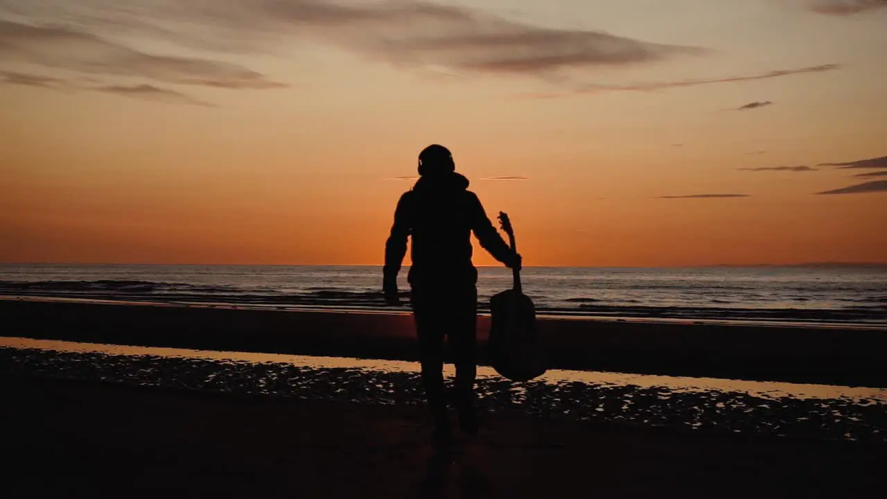 Man running with guitar in back sand beach at sunset-5