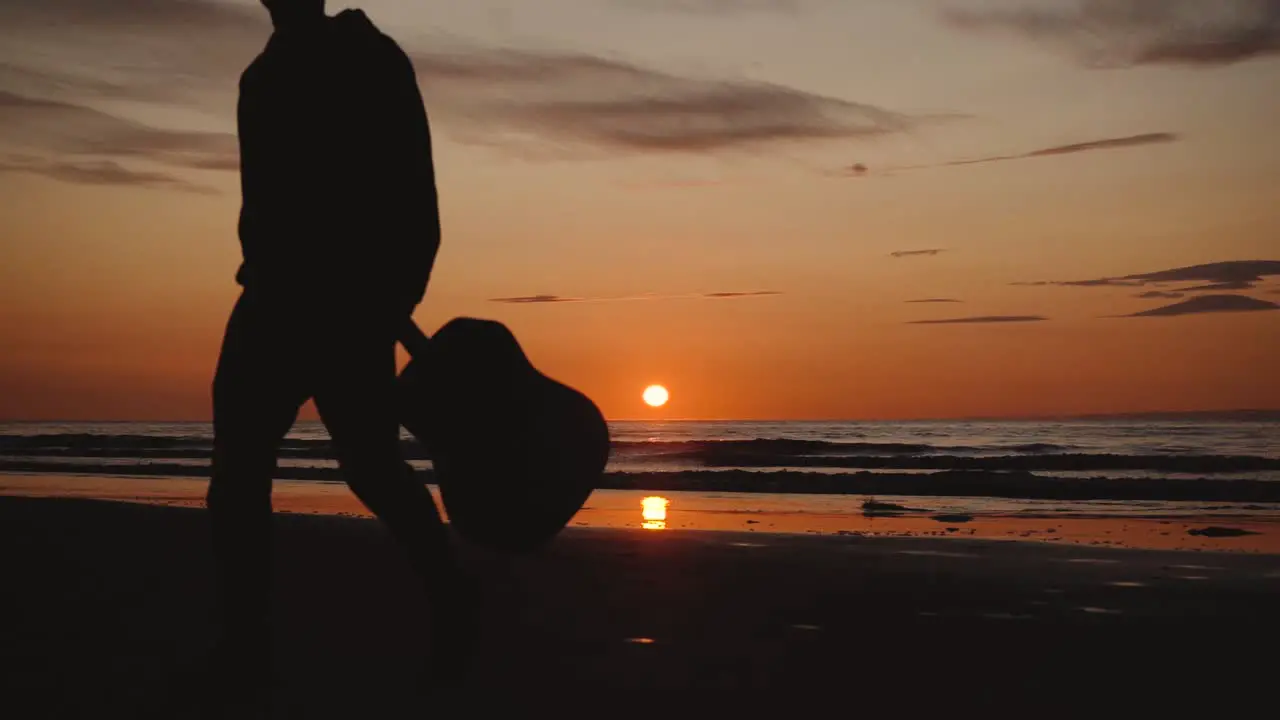 Man running with guitar in back sand beach at sunset-15