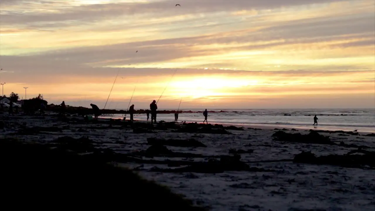 Men fishing on a beach at sunset