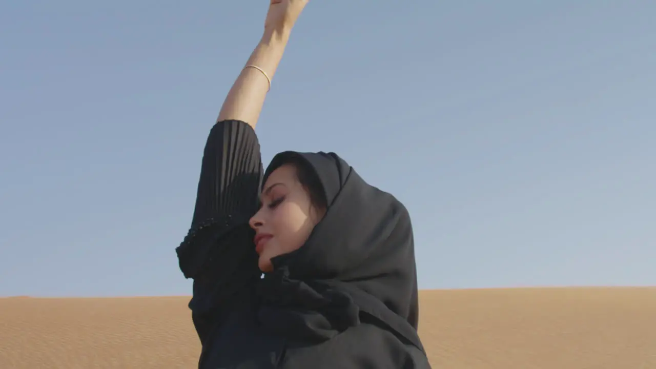 Muslim Woman Wearing Traditional Black Dress And Hijab Posing In A Windy Desert 2