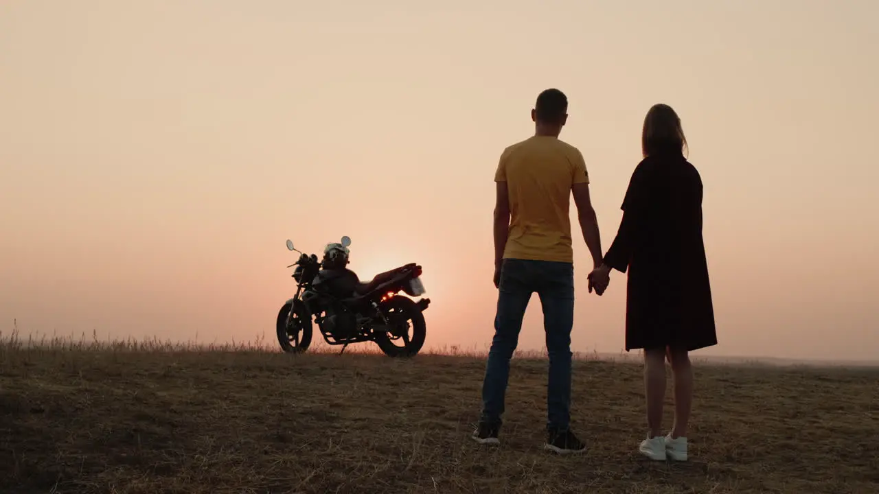 The romantic couple holds hands by a motorcycle