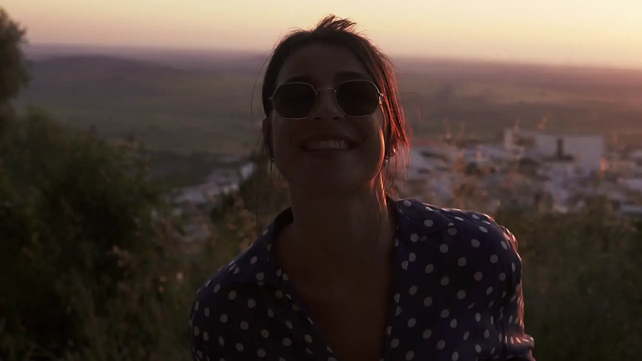 Model rotating in joy whilst watching the sun setting over a valley