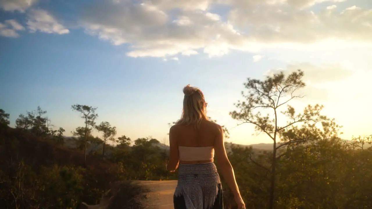 Gorgeous blond woman in summer clothes walks swaying her hips among the green tourist attraction of Pai Canyon on a summer day in Thailand