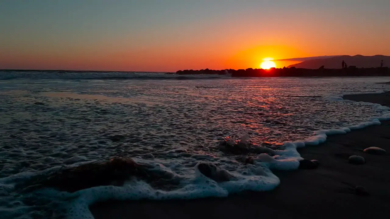 Low gimbal shot of beach at sunset showing close up of waves crashing at San Buenaventura State Beach in Ventura California United States