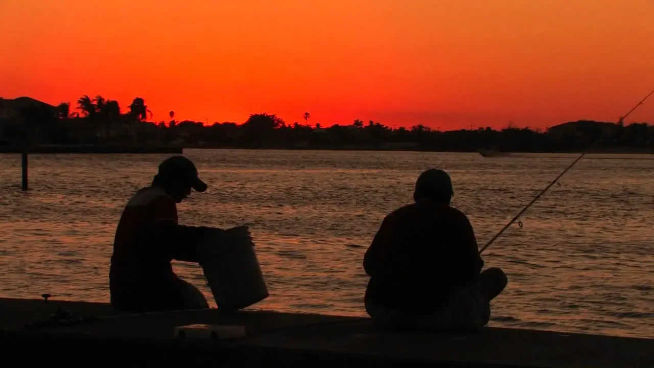 The silhouette of two men fishing at sunset