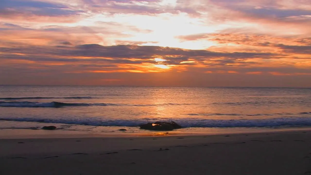 Beach waves slowly break during sunset 1