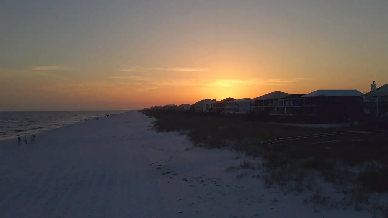 A Drone shot of the beach at sunset with a quaint little town in the background