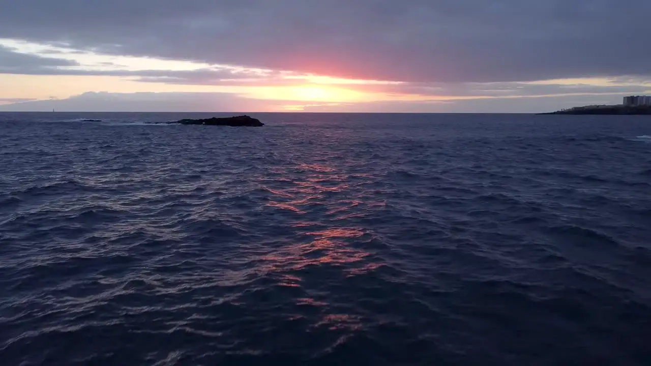 Drone aerial flying towards sunset with small fishing boat and seagull flying in front