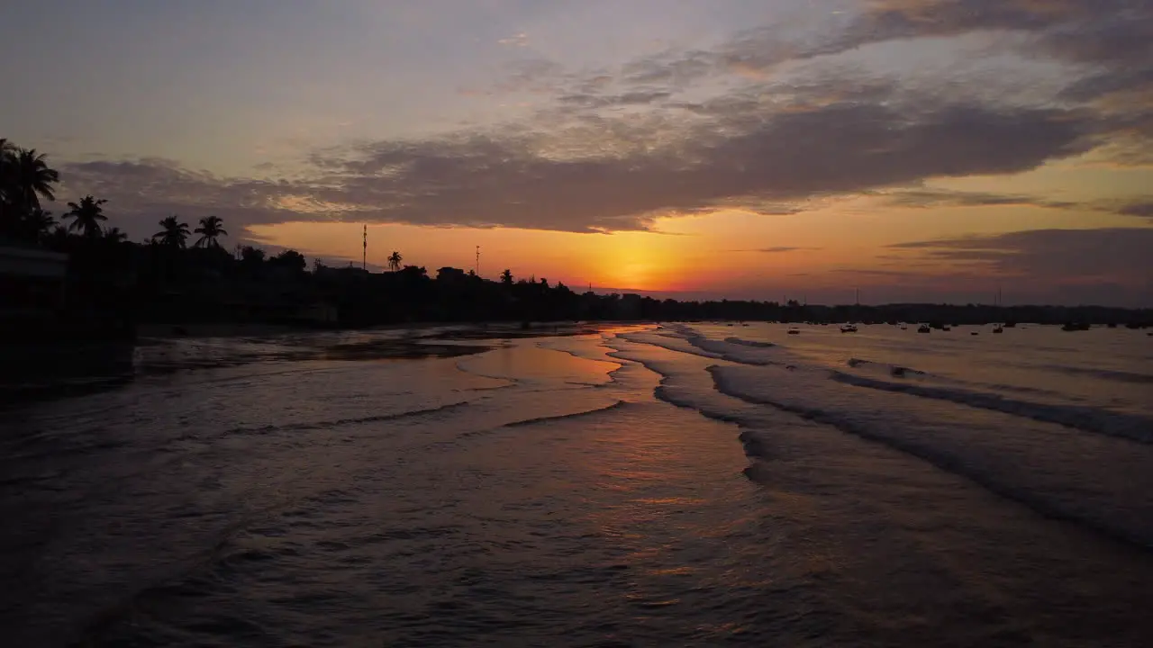 Aerial cinematic flyover calm ocean beach shore at dusk