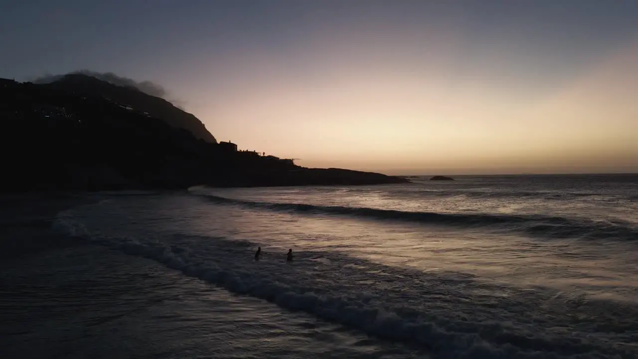 a couple playing with big waves at Sea over white sands of South African beach sunset time- aerial shot