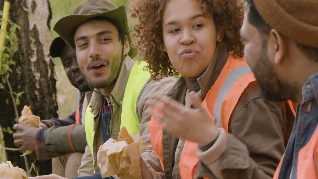 Close-up view of a group of multiethnic ecologist activists eating in a break in the forest