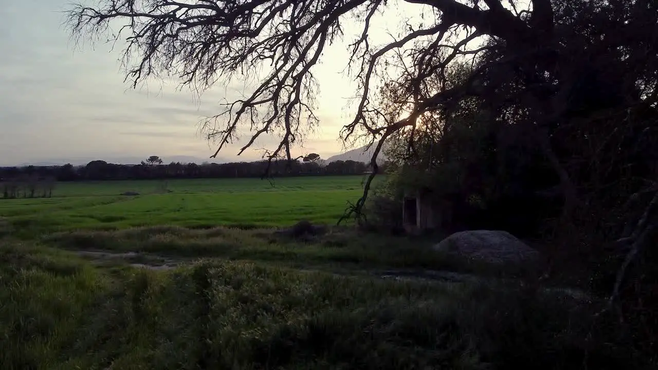 Pull in to enter an open green field to the view of the nice mountain in the horizon with the sunset in the back