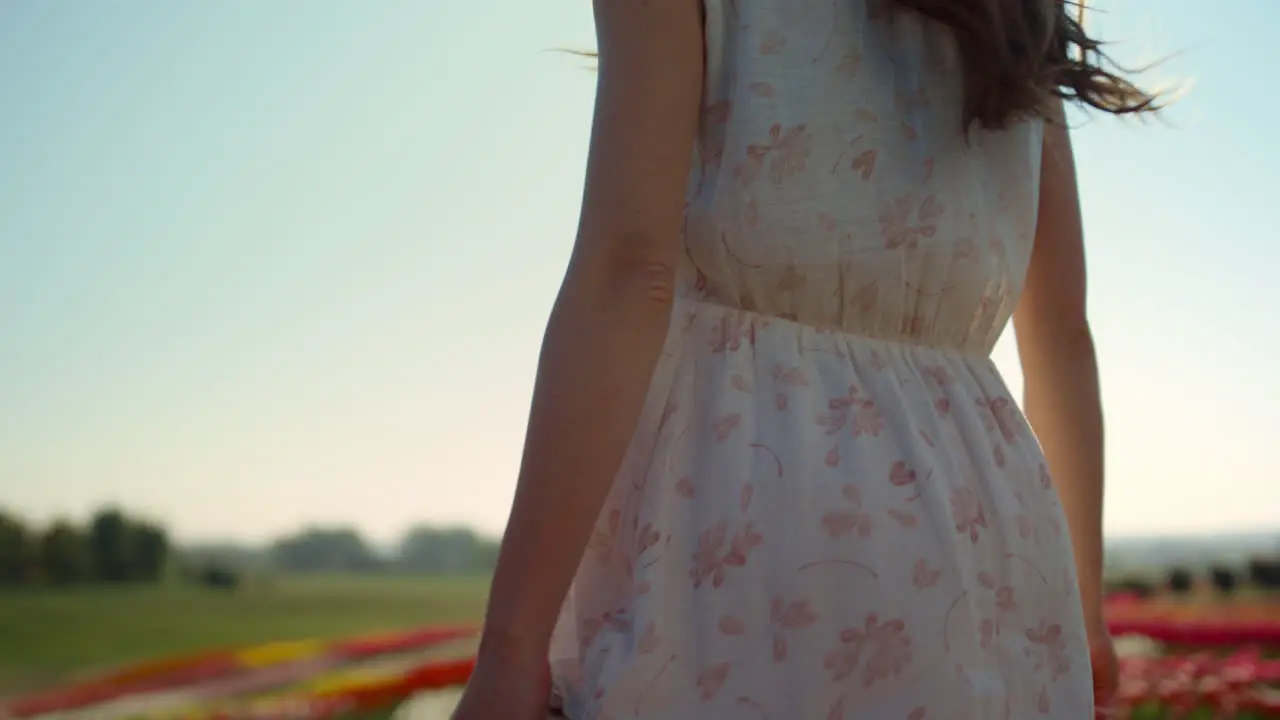 Unrecognizable woman with camera looking back at garden with spring flowers