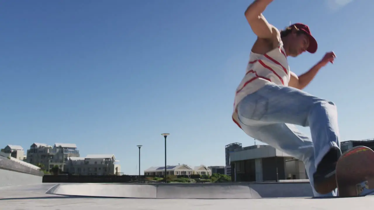 Caucasian man riding and jumping on skateboard on sunny day