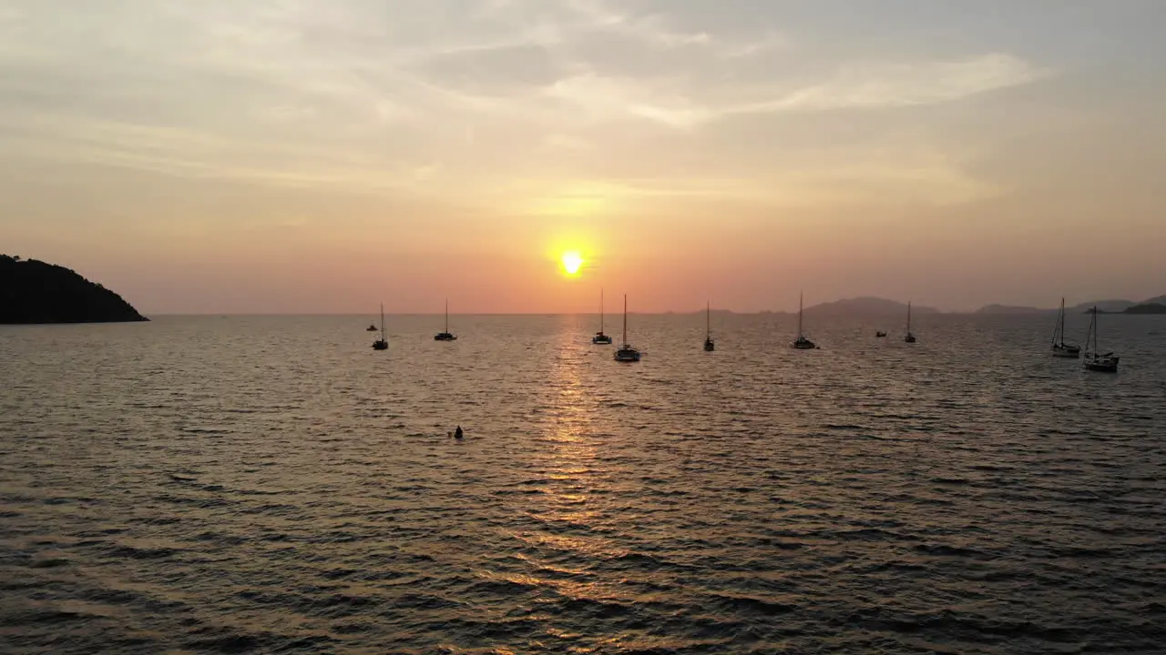 Flight over the ocean and boats with a golden sunset in the background