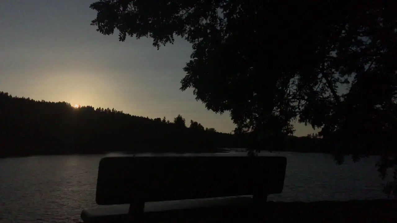 4k Handheld footage of a bench underneath a tree in front of a river at sunset in the Pacific Northwest of America