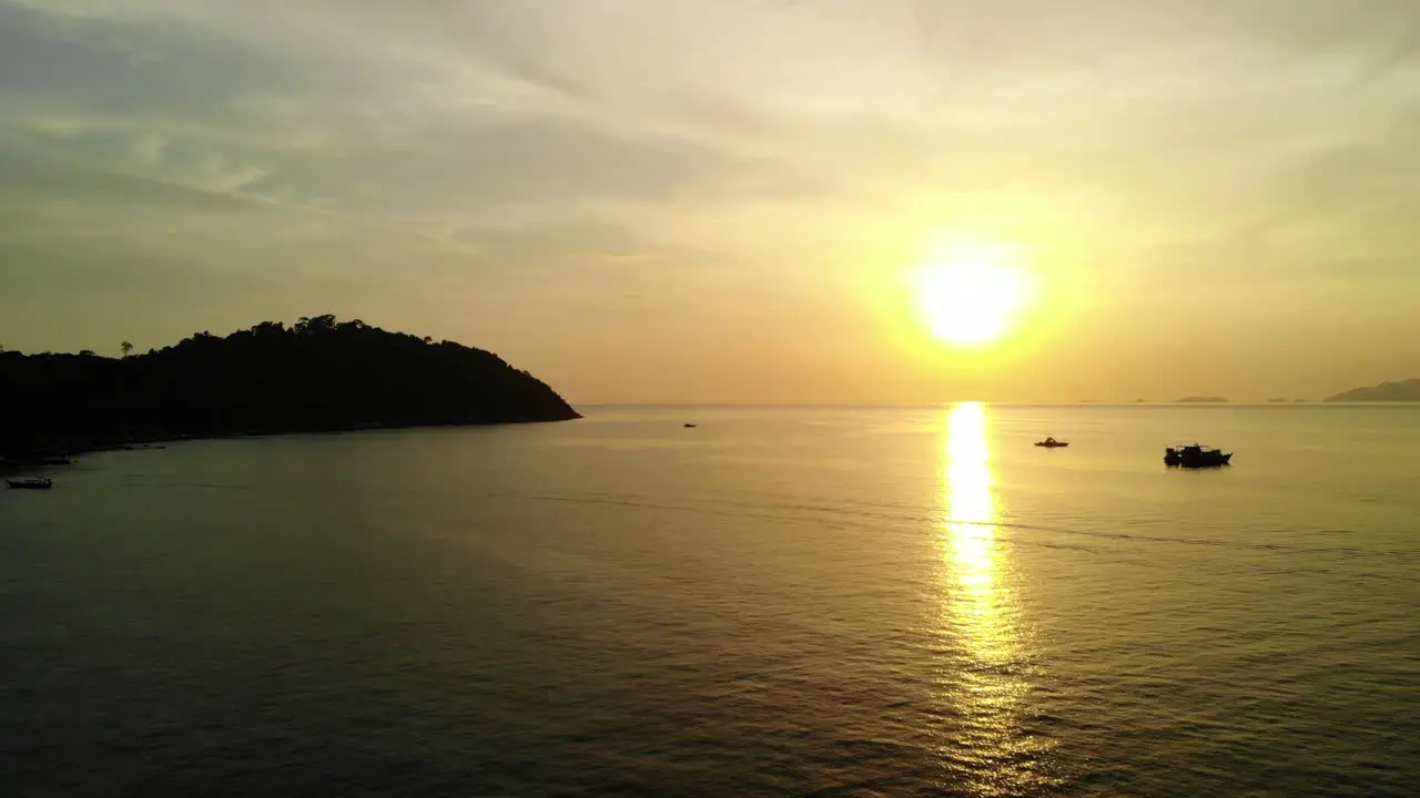 Peacefull ocean with a golden sunset boats and mountains in the background