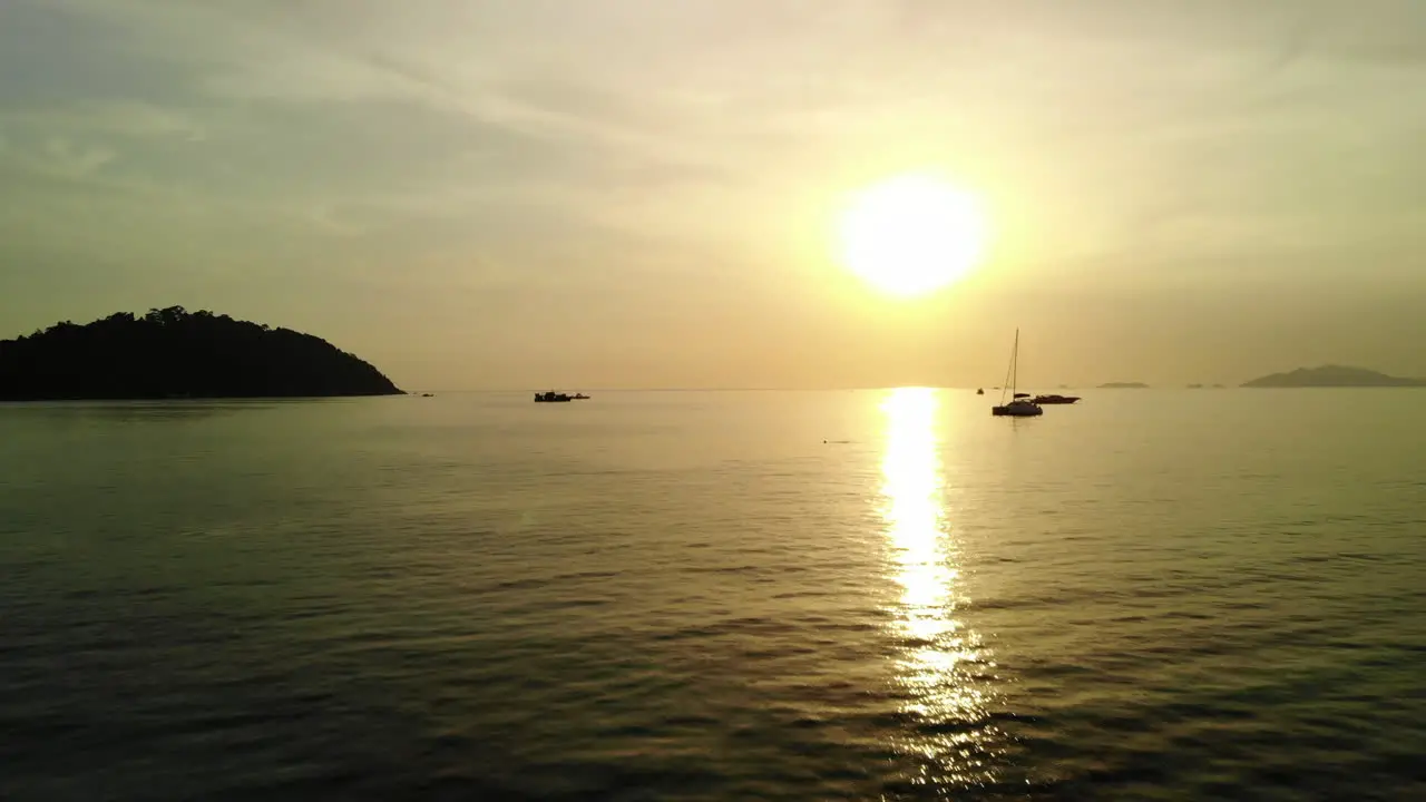 Low flight over the ocean with golden sunset and boats on the background