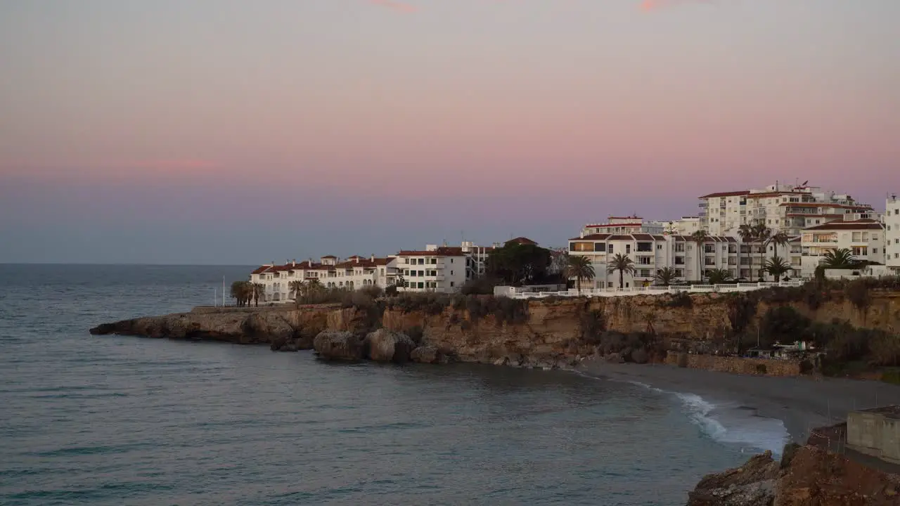 Beautiful white houses at pink sunset next to ocean and beach