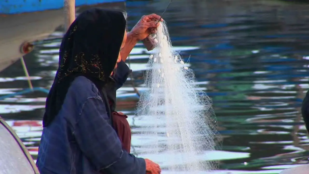 A woman works on her fishing net in Vietnam