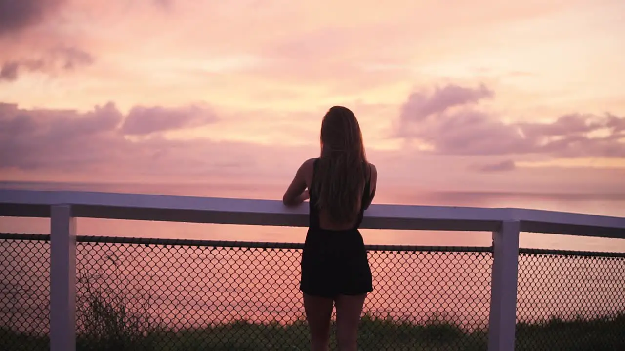 Female standing on ocean path at lookout in vibrant sunrise