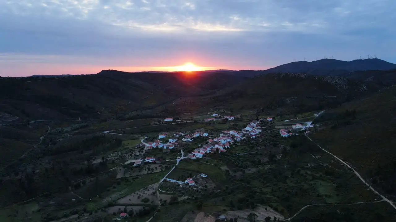 Drone view flying trough a small beautiful village in the mountains during sunset