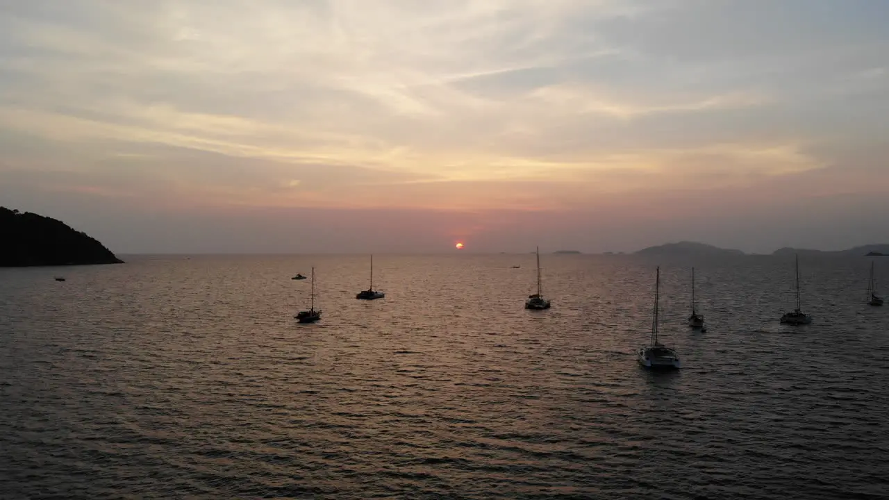 Flight over the ocean and boat with sunset and mountains in the background