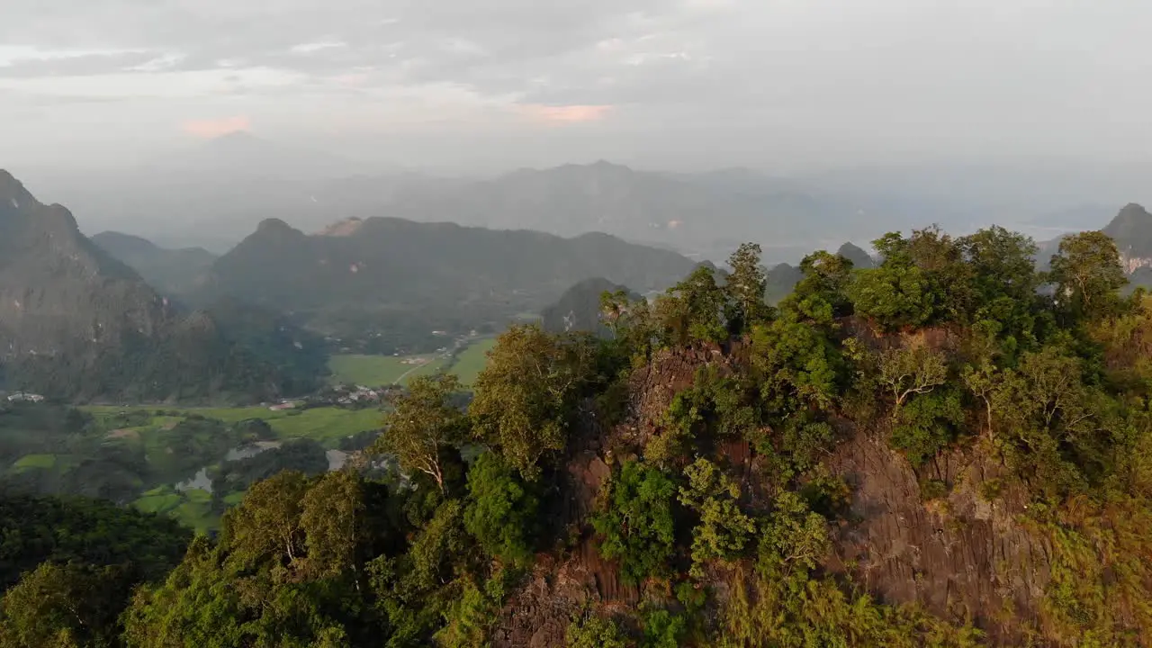 Aerial dolly in over a mountaintop to reveal the valley at Phong Lai Vietnam