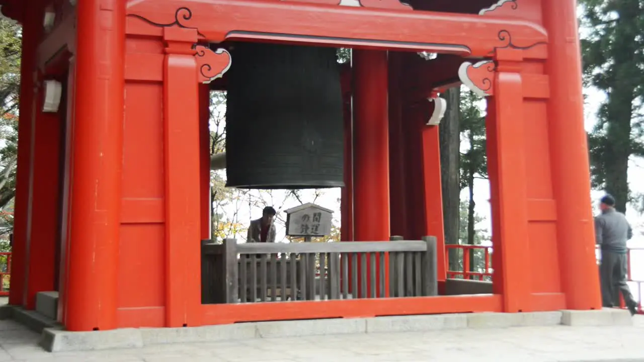 Japanese woman using a bell in a red shrine on mount Hiei-zan Kyoto Japan