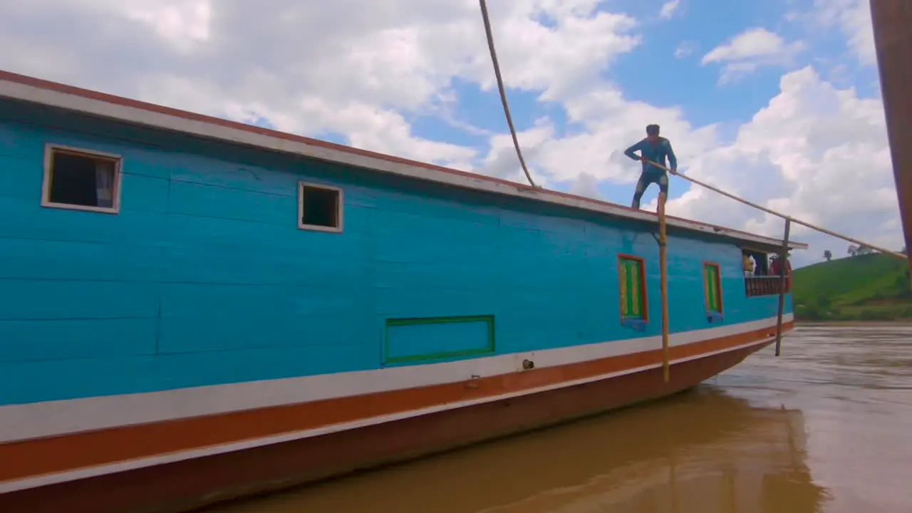 A local man pushes the boat away from the mooring launching it down the Mekong river with tourists on