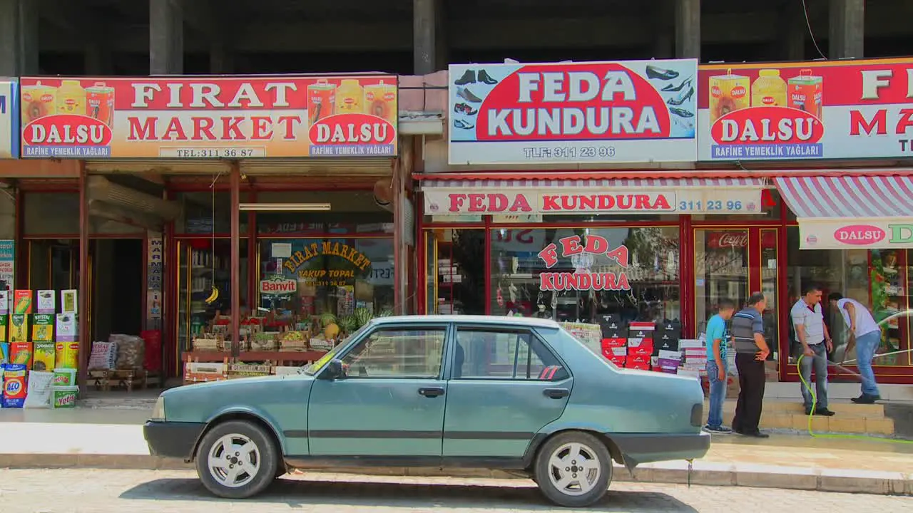 Car is parked in front of colorful shops and signs in a remote town in central Turkey