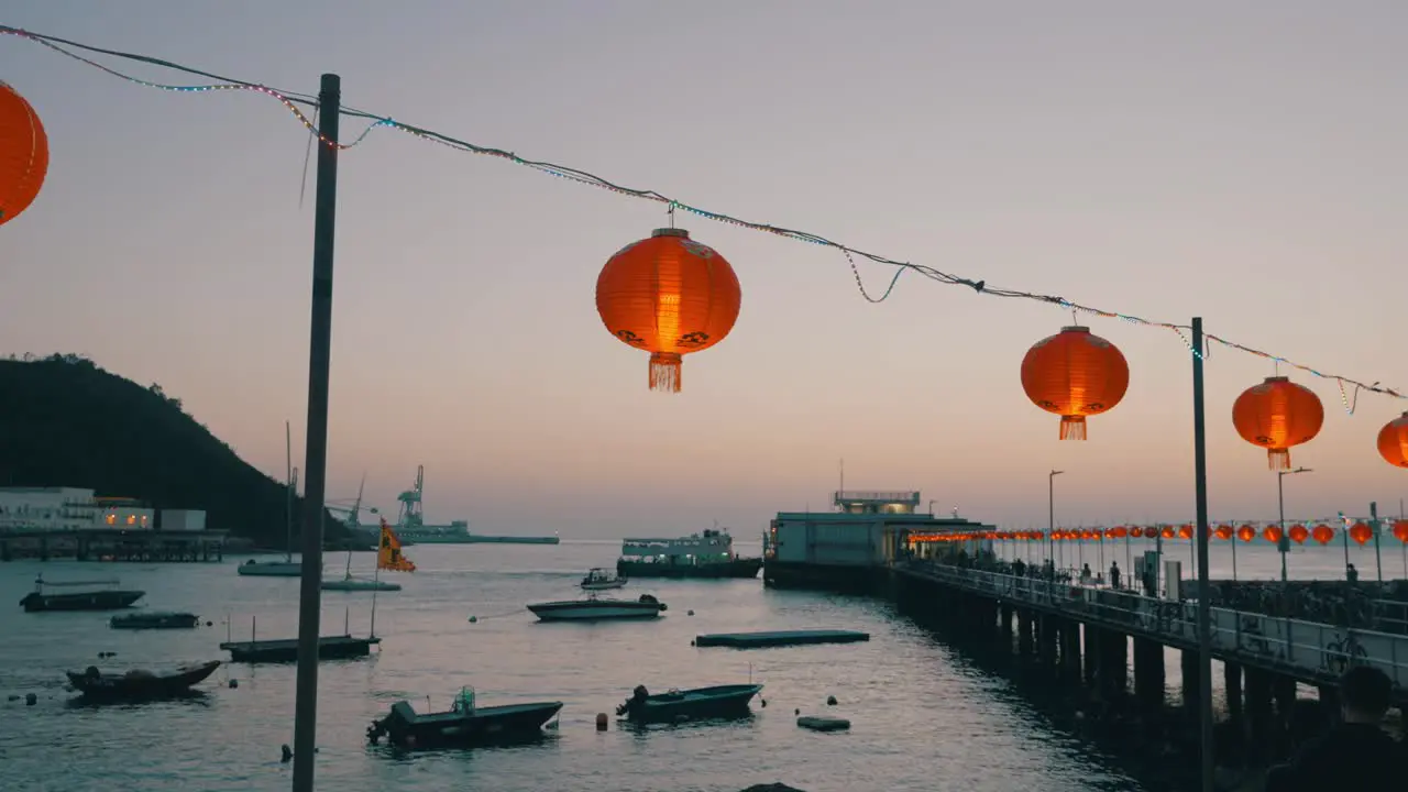 Shot of Chinese lanterns hang above the dock bridge of a small fisher village during sunset