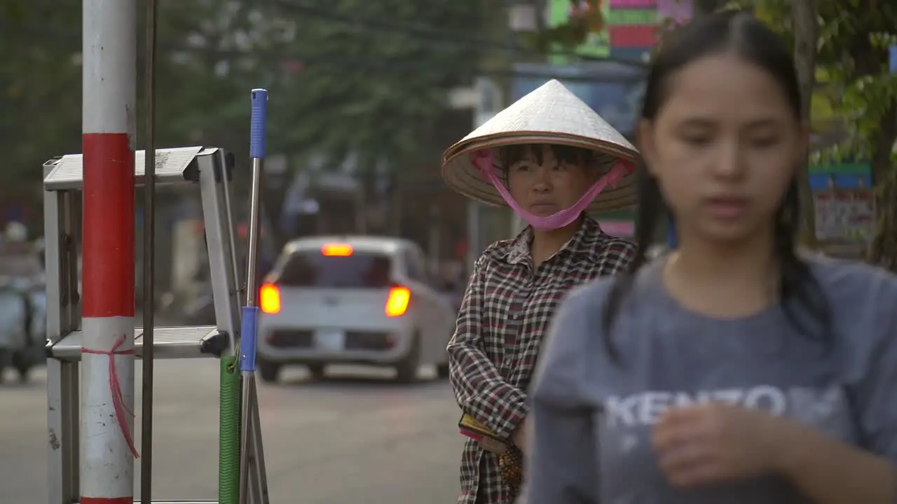 Vietnamese Lady Wearing a Conical Hat stood on a Busy Street