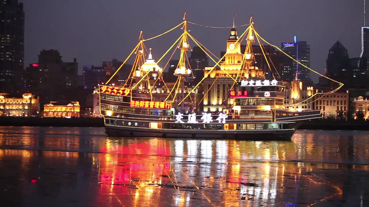 The night skyline of Shanghai China with river traffic foreground and illuminated tall ship passing 1