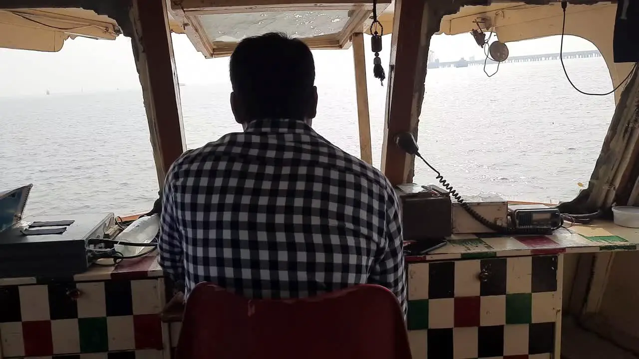 A boat driver on the top deck of a tourist ferry from Mumbai to Elephanta island near Mumbai India