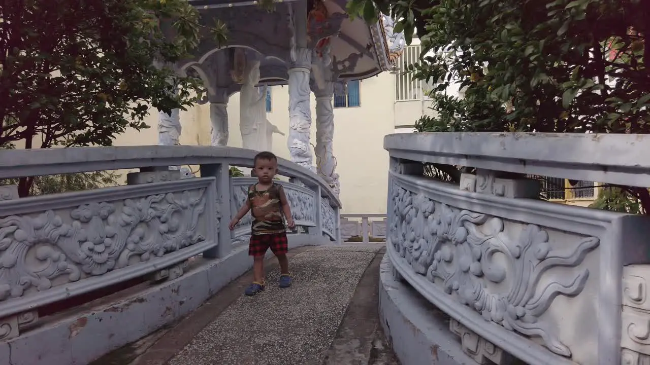 Young Boy walking on bridge over pond of Buddhist Temple in Suburban area of Ho Chi Minh City Vietnam