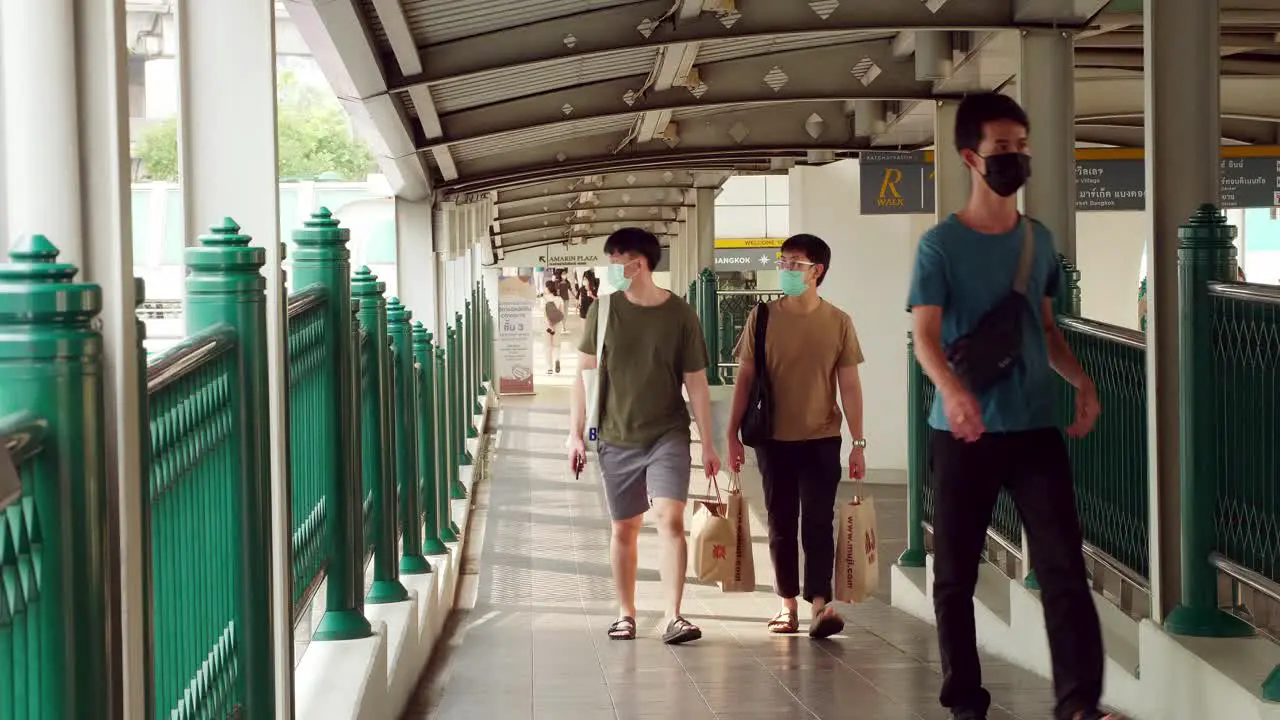 People wearing masks walk on a bridge connecting the central mass transit system during the COVID-19 pandemic