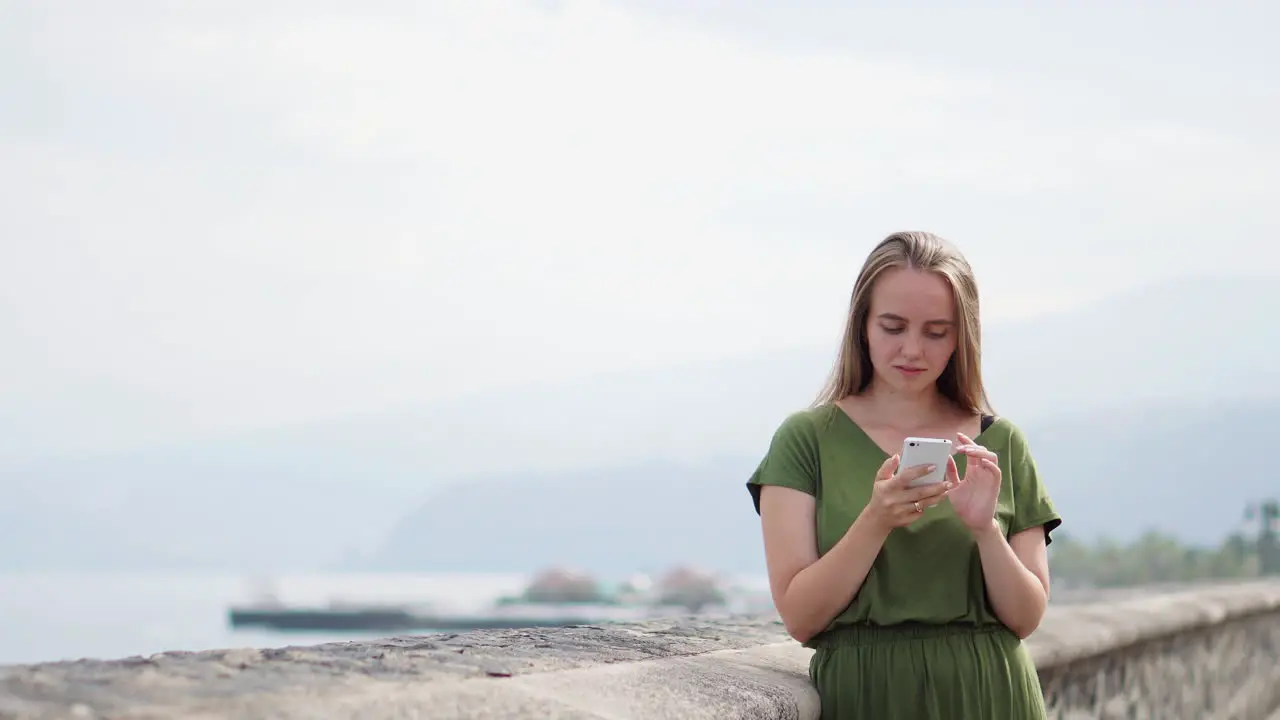 Woman on smart phone gadget in sand coastline Traveler using in female hand mobile on background beach seascape horizon Tourist look on blue sun ocean summer lifestyle