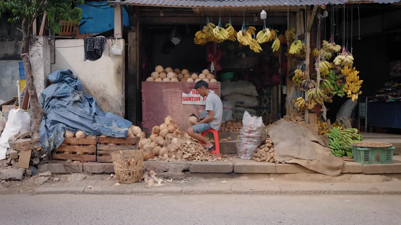 Tracking Shot Pulling Away from Young Man Shaving Coconut Coir Fibre