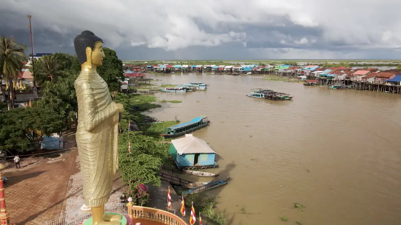 Giant Buddha statue overlooking flooded floating village during Southeast Asia monsoon season